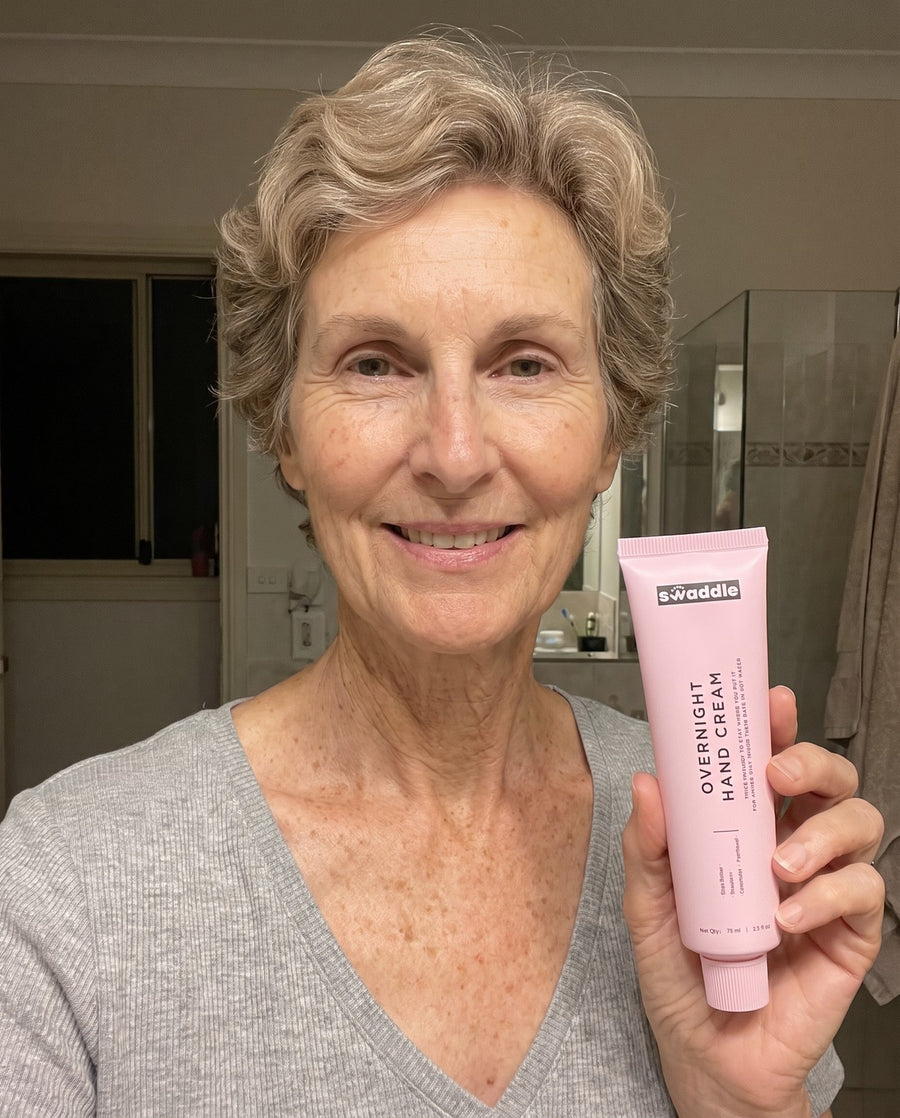 A woman holding the Swaddle Overnight Hand Cream before bed