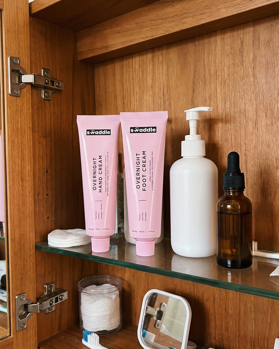 Swaddle Overnight Hand Cream and Overnight Foot Cream on a bathroom cabinet shelf